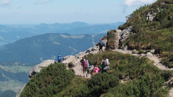 Group of Tourists and Children with Backpacks Go Down on Stone Trail in Mountain