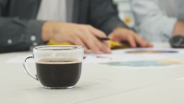 A Cup of Coffee on the Table Businesspeople Working on the Background