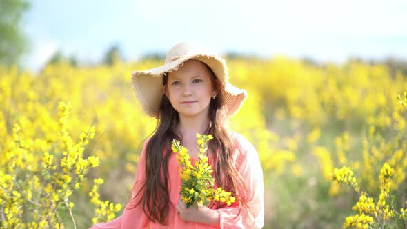 Young Girl Walks in a Rapeseed Field.