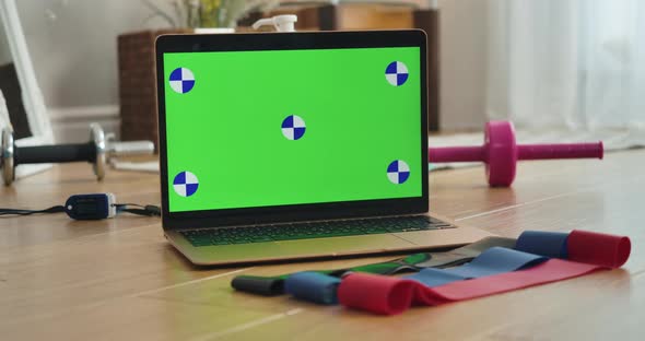 Chromakey Laptop Screen with Female Hand Taking One of Resistance Bands Lying on the Floor