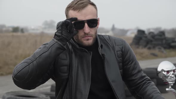 Portrait of Biker Undresses Sunglasses and Looks Seriously at Camera