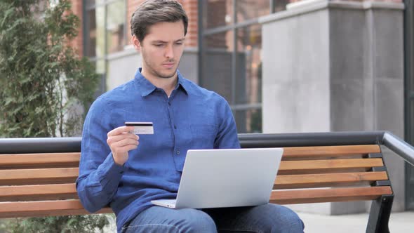 Online Shopping by Young Man Sitting on Bench