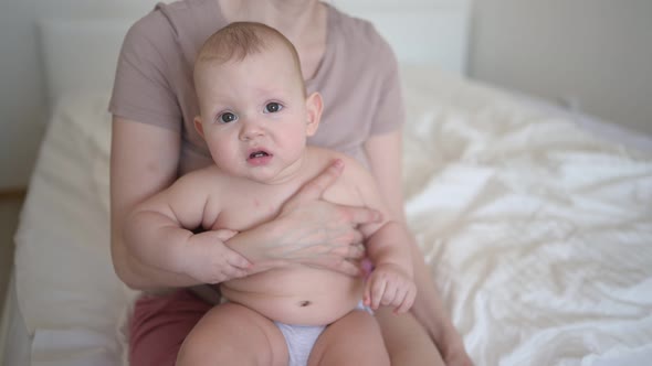 Cute Infant Toddler Boy Learns to Walk First Steps on Bed and Playing with Mother Early in Morning