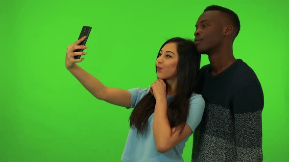 A Young Asian Woman and a Young Black Man Take Selfies - Green Screen Studio