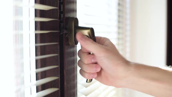 the man opens the window for ventilation and fixes the degree of disclosure