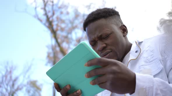 Portrait of Stressed Surprised African American Man with Digital Tablet in Autumn Park Outdoors