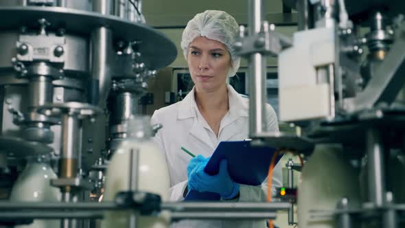 Woman Checks Bottles with Milk on a Industrial Food and Drinks Plant Conveyor