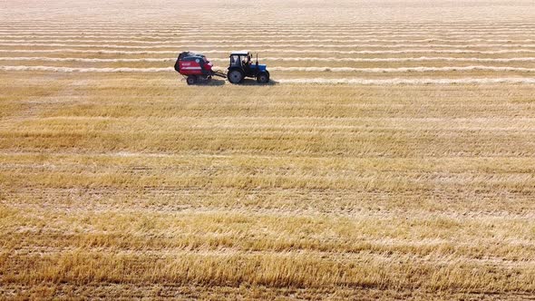 The tractor roll up the straw and releases a packed round bale on agricultural field