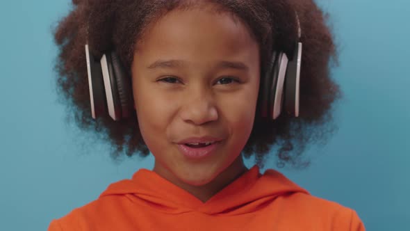 Cute African American girl enjoys singing song and listening the music in headphones