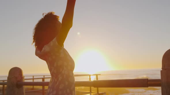 Woman standing with her arms wide open at sunset