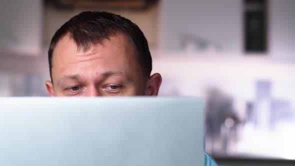 A Man in Surprise Raises His Eyebrows Reads News on the Internet in His Laptop