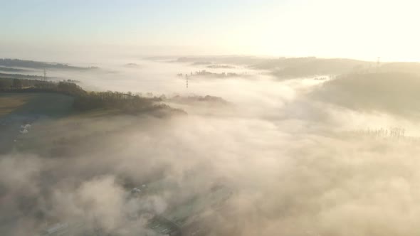 Bright, misty sunrise in west Germany. Aerial tracking shot of valleys filled with thick fog