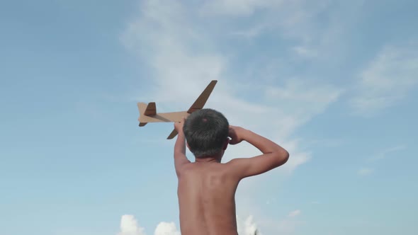 Asian Poor Boy Playing A Cardboard Airplane