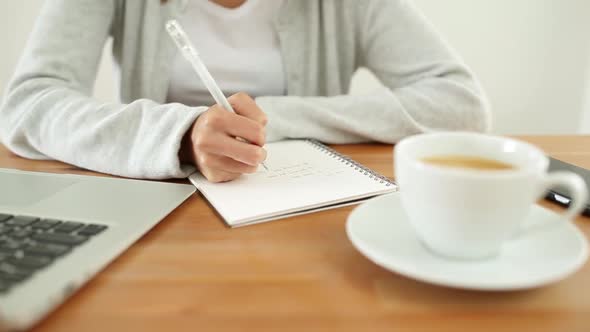 Woman writing on notebook on her desk