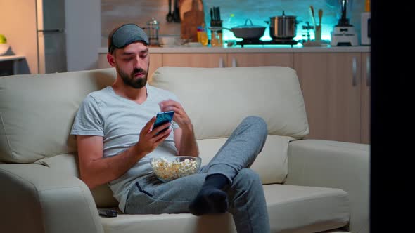 Bored Man Sitting on Couch Holding Popcorn Bowl