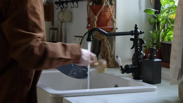 woman washes a plate in the kitchen using eco-friendly brushes