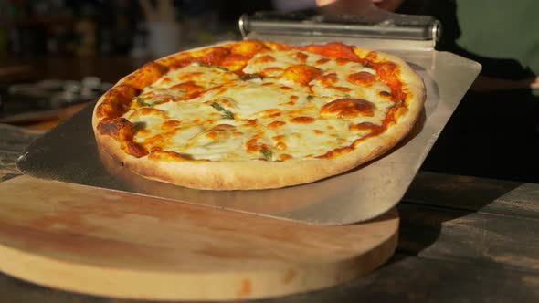 Chef Cook Take Out Freshly Baked Pizza Pie with Metal Peel Places It on Plate