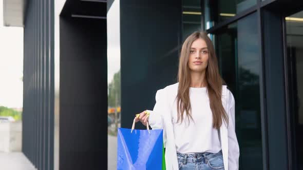 Young Beautiful Woman Walking Near the Store with a Package of Food or Clothes