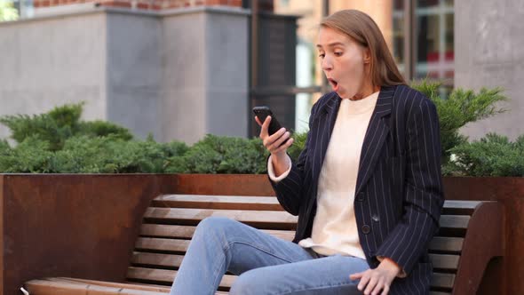 Business Woman in Shock Reacting to Results on Smartphone