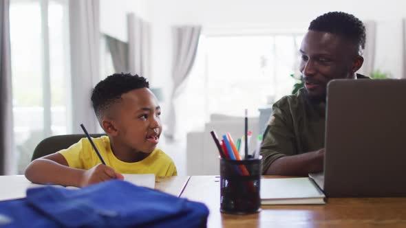 African american father and son doing homework and using a laptop together