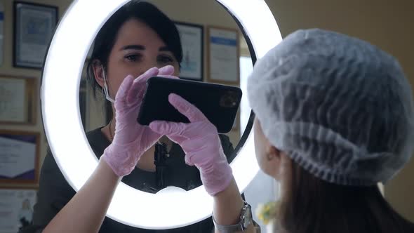 The Beautician Photographs the Client's Lips on the Phone After Lip Tattooing for Advertising on