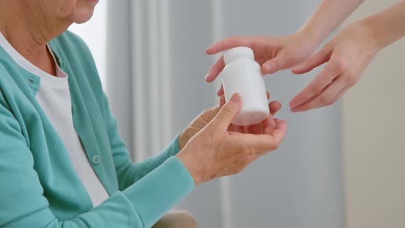 Mature woman patient takes blank white bottle of medicine