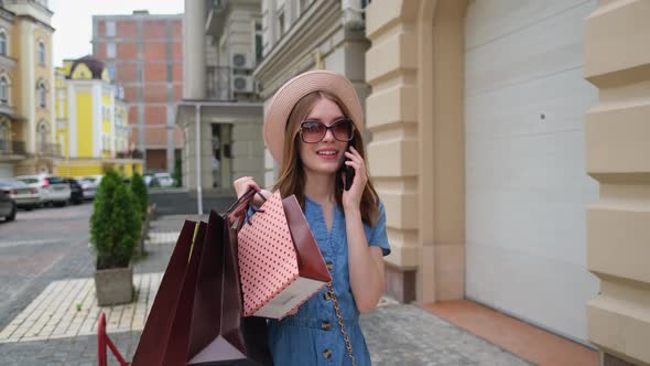 Young Woman with Shopping Bags Walking in a City at Summer Day