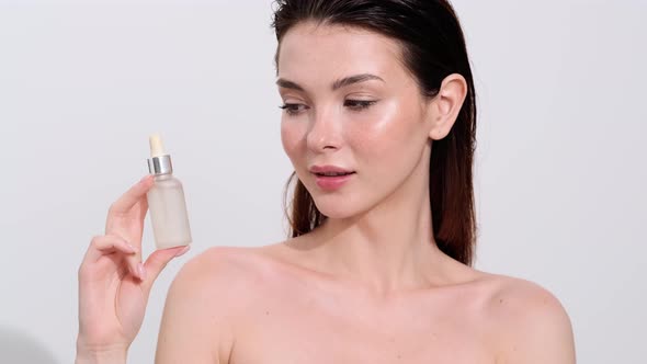 A half-naked brunette woman posing with a hyaluronic face serum