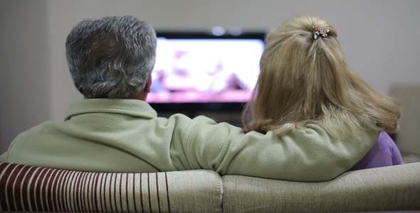 Couple Sitting Together On Sofa, Watching TV