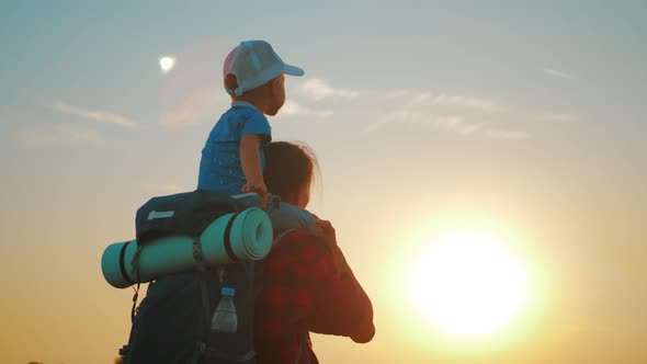 Mother and Little Son Silhouettes Playing on Meadow. Boy Raising Up Hands Imitating a Flight at