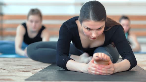 Group of Young Sportive Women Doing Stretching Exercises on the Floor