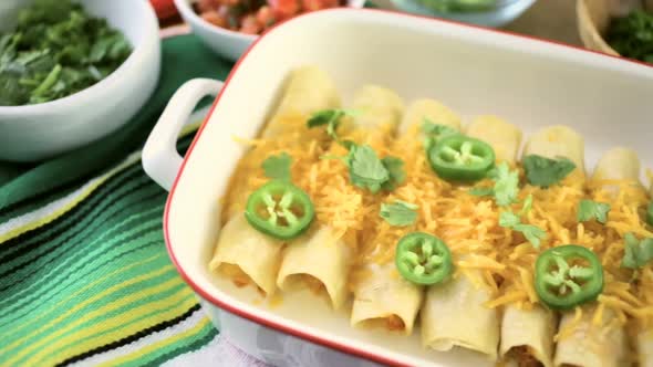 Chicken enchiladas with cheddar cheese and sauce.