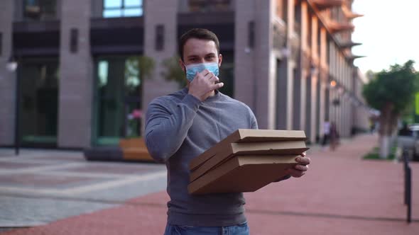 Portrait of cheerful delivery man take off protective medical mask, standing, looking at camera.