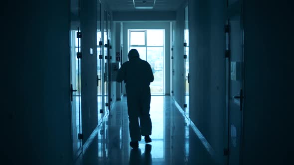 Paramedic in a Safety Suit Is Having a Break in the Hall