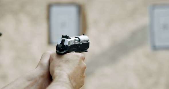 Slow motion of a hand gun firing in a firing range with cartridge flying away