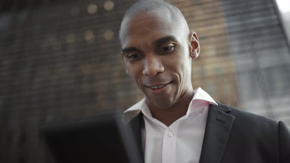 Laughing African businessman listening voice message on mobile