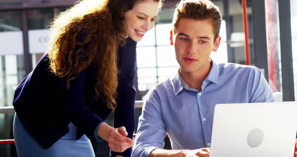 Business executives discussing over laptop