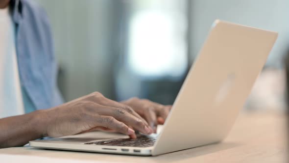 Hands of African Man Typing on Laptop Keyboard