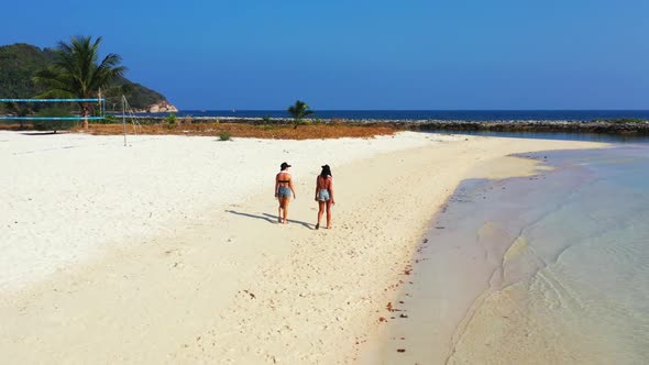 Girls relaxing on tranquil tourist beach holiday by blue ocean and white sandy background of Thailan