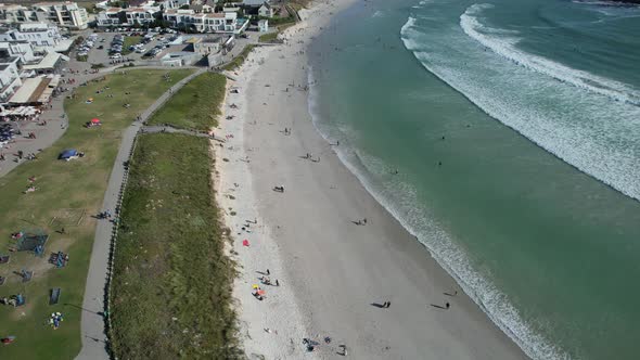 people enjoy summer day at Big Bay Beach in Cape Town, South Africa