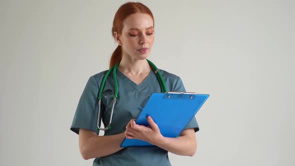Medium Shot Portrait of Confident Female Physician in Green Medical Uniform Writing Notes on