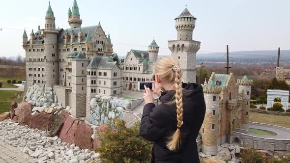 Woman Makes Photo Walking on Foot Near a Miniature Model of the Old Castle Neuschwanstein, Germany