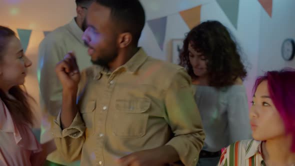 African American Man Dancing with Friends Enjoying Night Party in Decorated Apartment