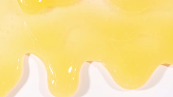 Yellow Cosmetic Gel Fluid Flowing Down on a White Surface