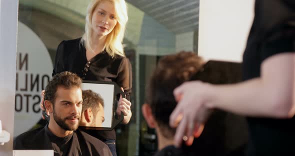 Female hairdresser showing man his haircut in mirror