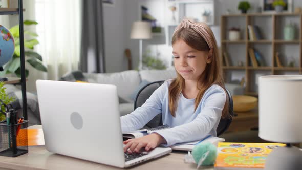 Little Girl Behind a Laptop on an Online Lesson at Home in the Living Room