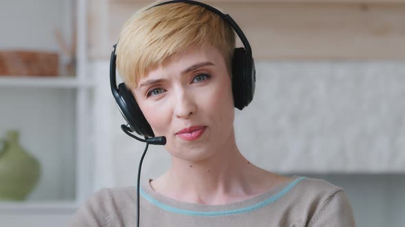 Millennial Woman in Headphones Looks at Camera Talking By Videoconference with Colleagues