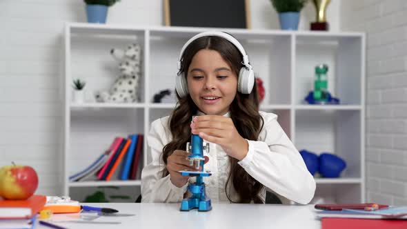 Curious Child in School Uniform and Headphones Use Microscope School