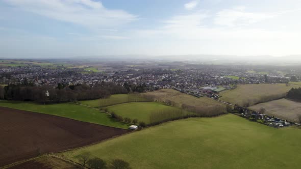 Aerial Drone flying over ploughed and grassy fields towards Blairgowrie and Rattray, Scottish Farmin