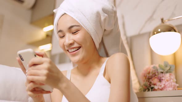 Happy attractive asian woman apply skincare cream on face and body